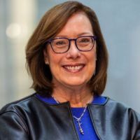 Portrait of a woman with glasses smiling in professional attire.