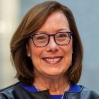 Portrait of a smiling woman with brown hair and glasses, likely a researcher in oncology.