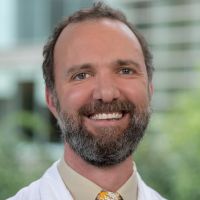 Portrait of a smiling researcher in a lab coat.
