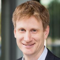 Portrait of a researcher with short blonde hair smiling for a professional headshot.