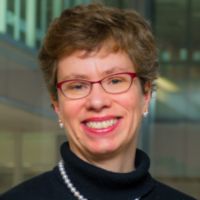 Portrait of a smiling researcher with glasses and short hair in a professional setting.