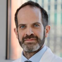 Portrait of a researcher in a lab coat, looking at the camera with a serious expression.