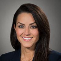 Portrait of a smiling researcher with long dark hair and a navy blazer.